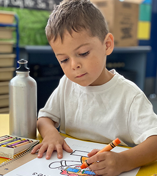 Young boy coloring at his desk